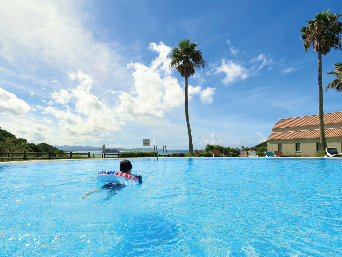 An outdoor pool with a view of check-in and sea!